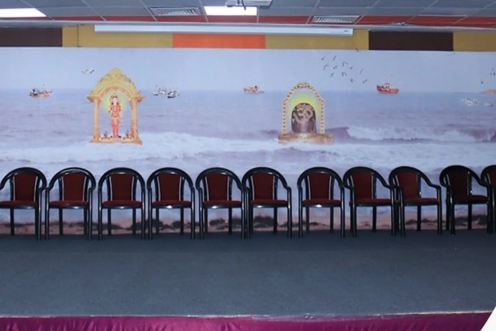 Hall stage with chairs along the back wall and a sea mural behind